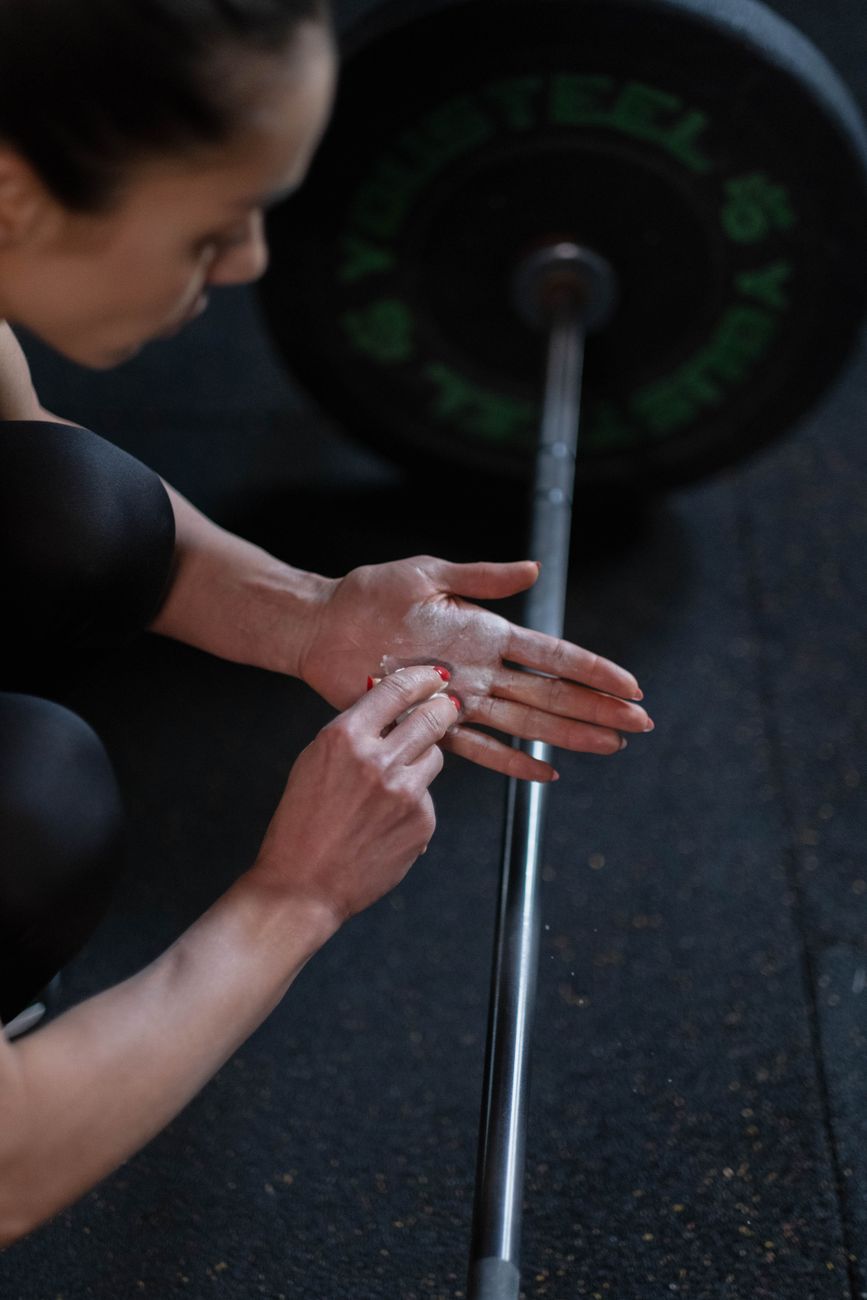 Chalked hands gripping a knurled barbell shaft.
