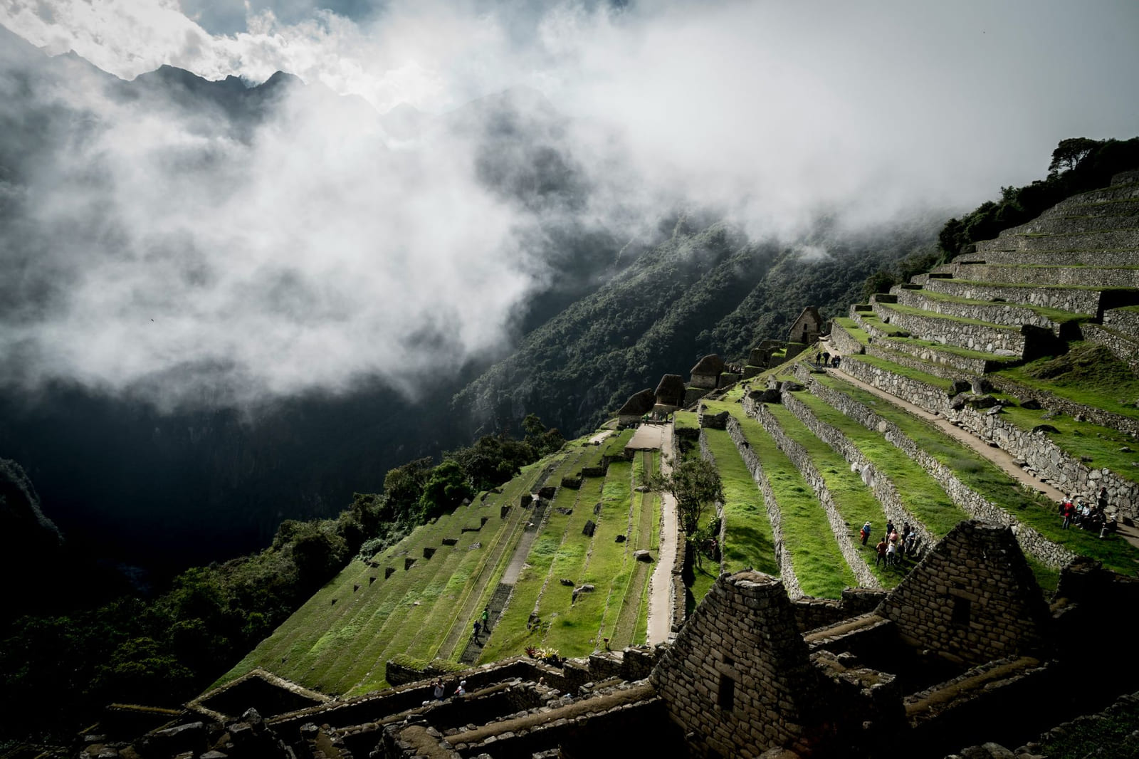 The terraces of Machu Picchu emerge through morning mist, the mountain falling toward the valley