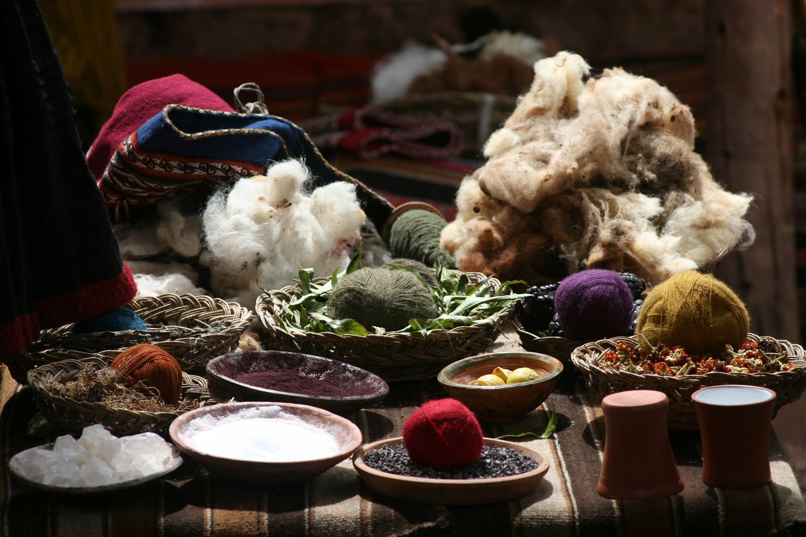 Baskets with alpaca fiber, yarn balls and natural dyes on a weaver's table