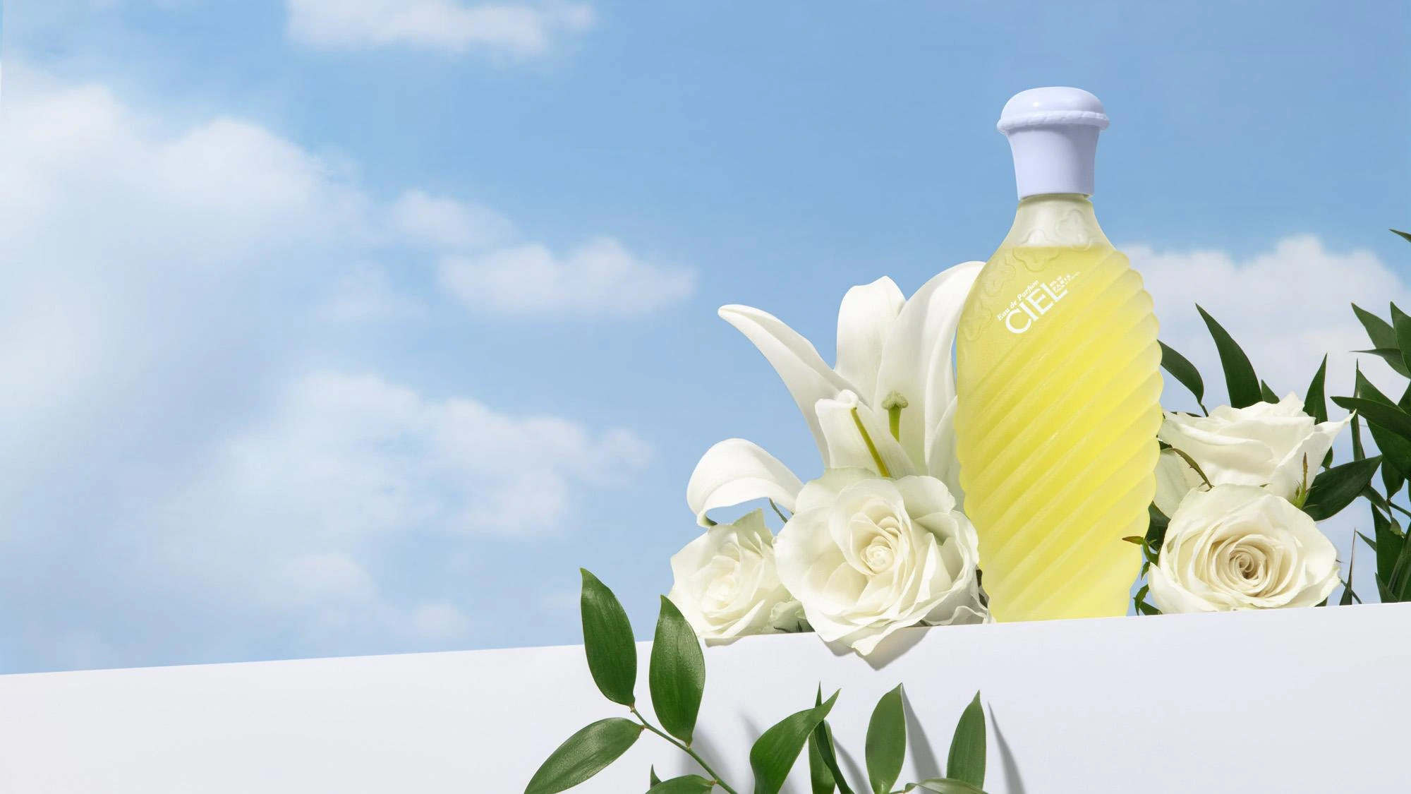 Ciel bottle with white lilies and roses against a blue sky